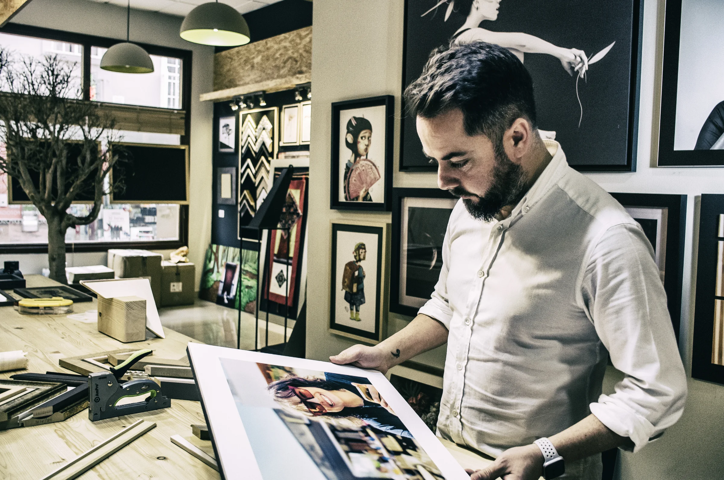 Julio Castellana revisando una fotografía enmarcada en el showroom